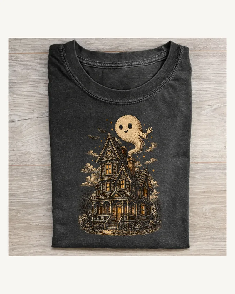 Folded washed black T-shirt featuring Unexpected Guest on a pale wood tabletop