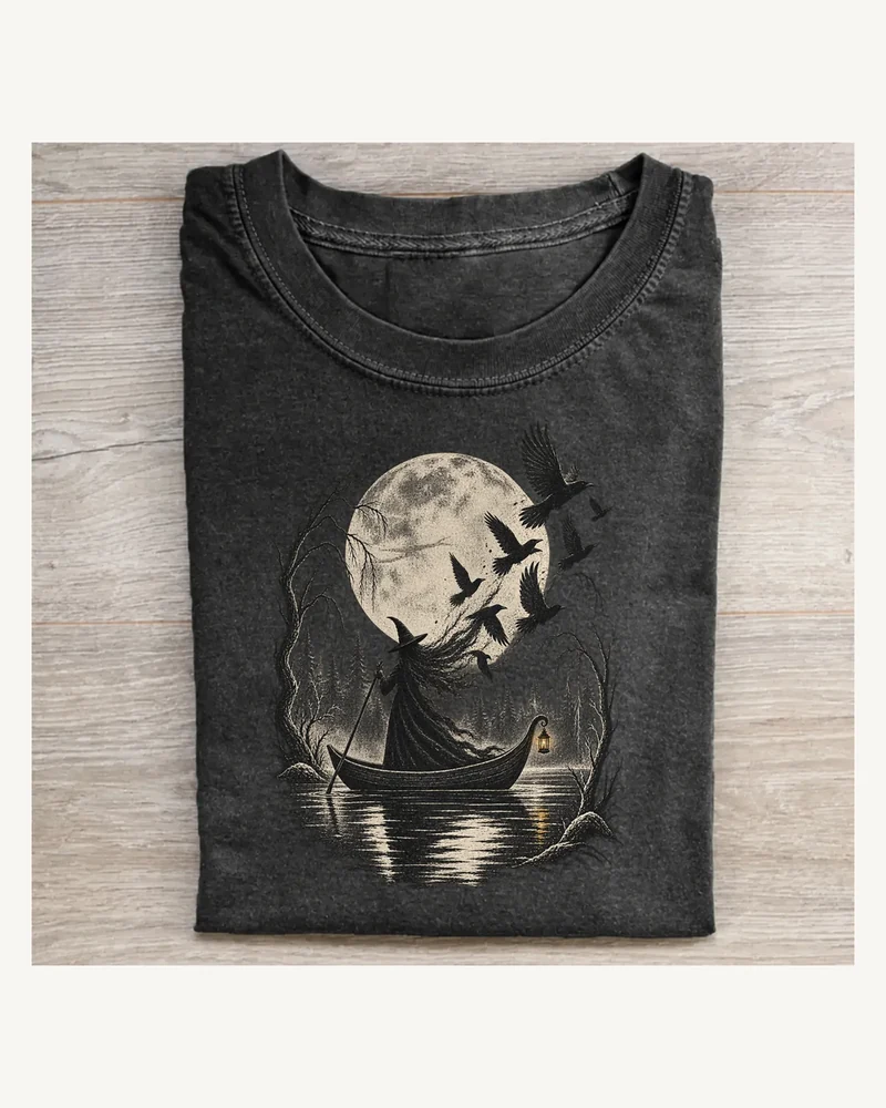 Folded washed black T-shirt featuring Raven Ferry moonlit witch artwork