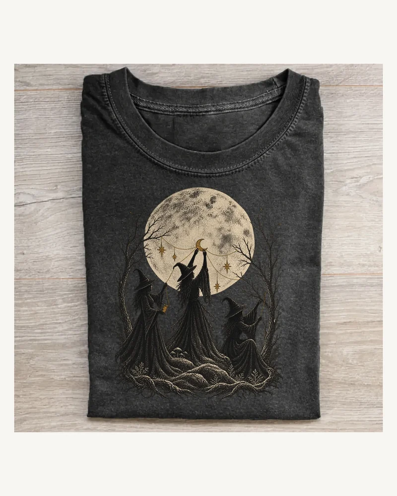 Folded washed black T-shirt featuring Moon Weavers moonlit witch artwork